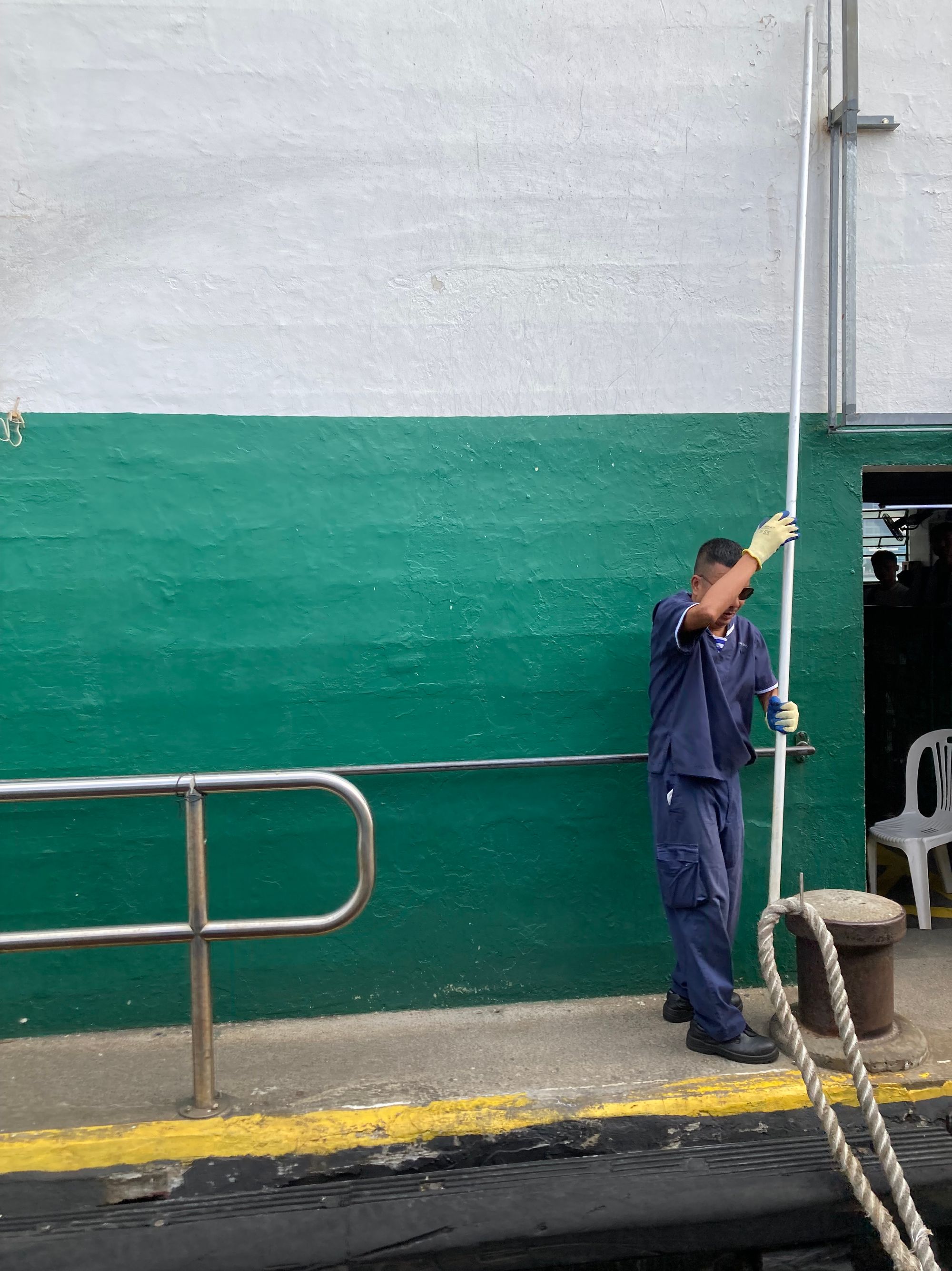 A Star Ferry sailor grabs the ferry's docking rope with a hook.