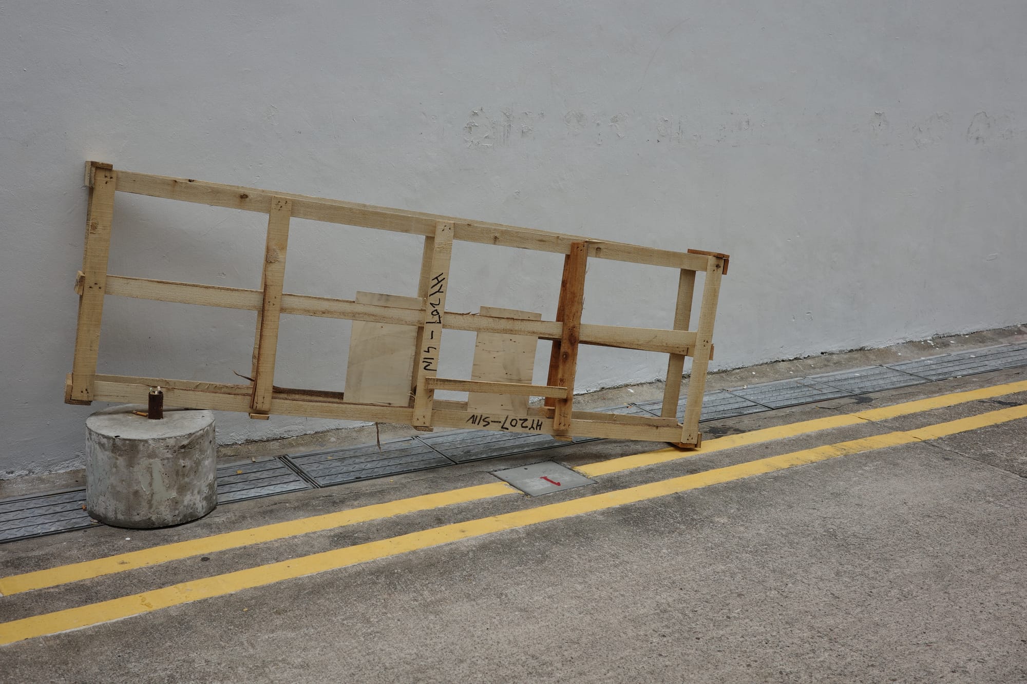 An abandoned wooden pallet is balanced at one end on a concrete ballast