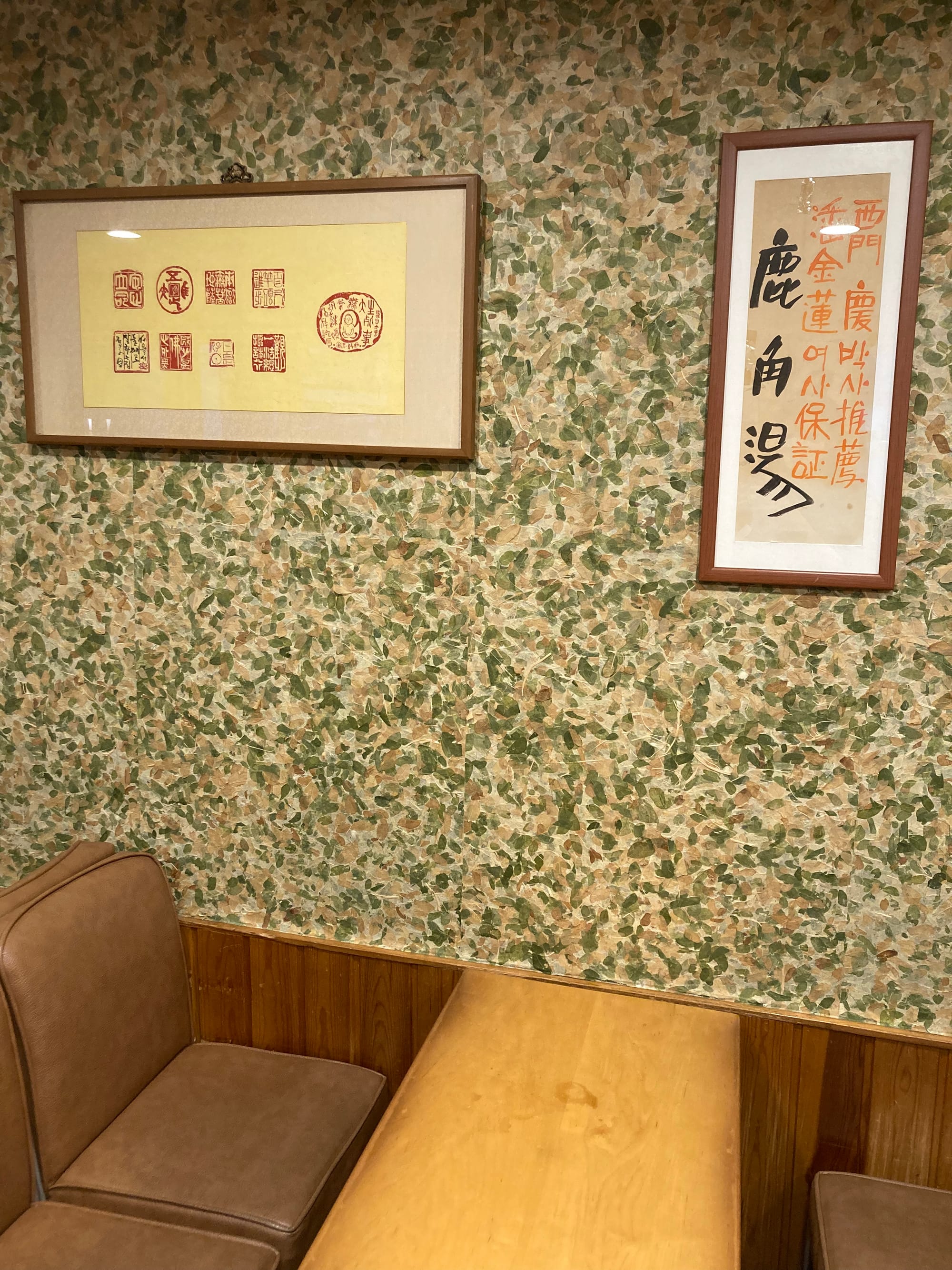 Interior shot highlighting two traditional Korean ink pieces on the green and brown-flecked wallpaper