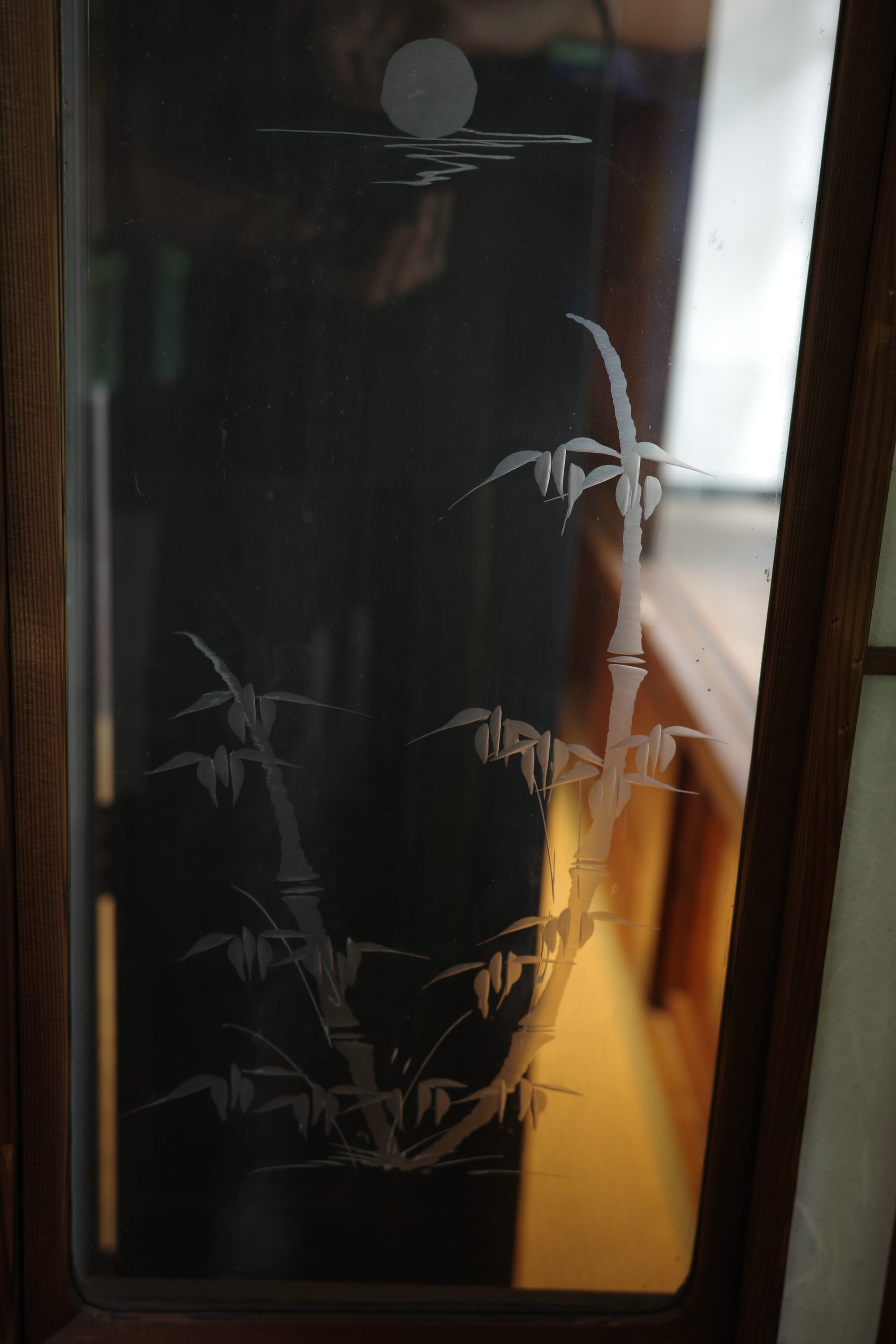 Close up of 2 sprigs of bamboo etched on an indoor glass partition. 