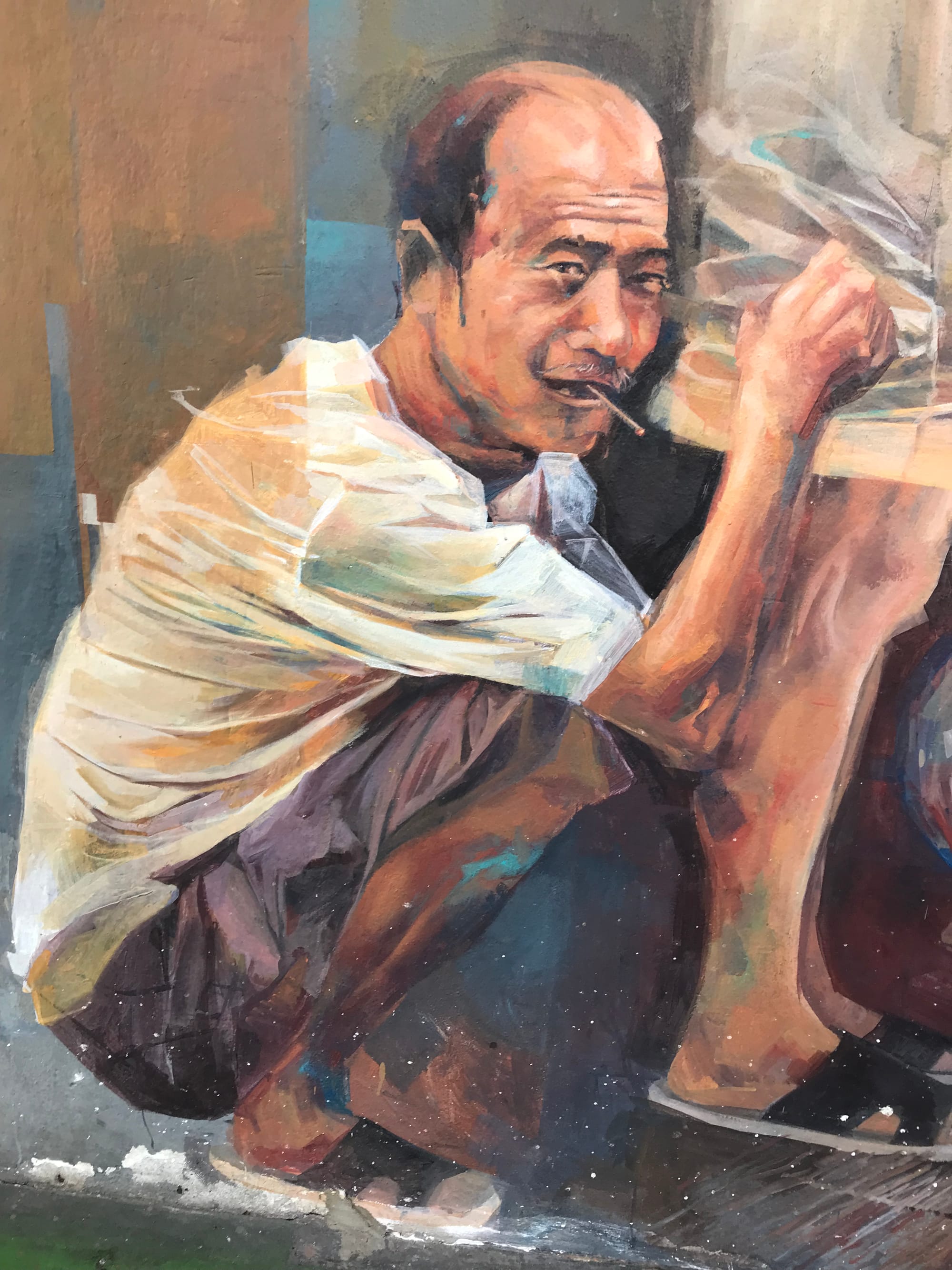 Mural of a balding man squatting and looking at the viewer with cigarette in his mouth.