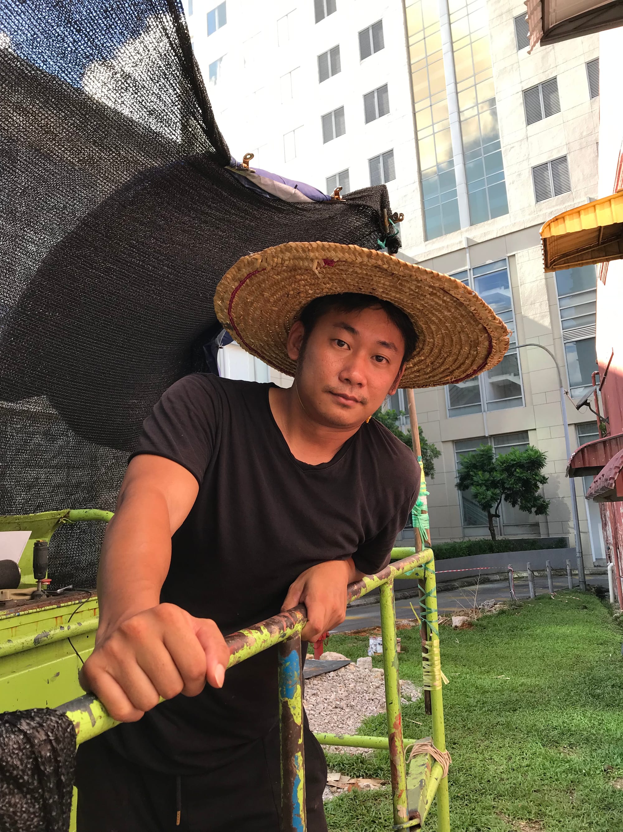 A young man in a straw hat and black clothes on a boom lift