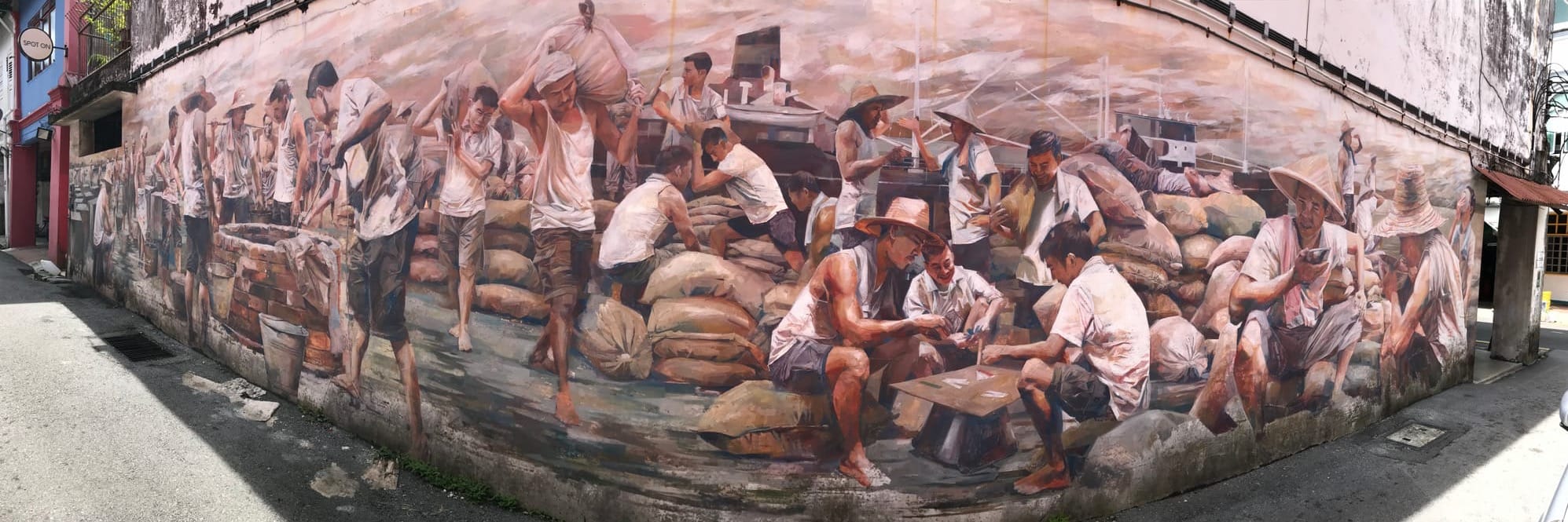 A panoramic shot of a mural about Chinese labourers carrying loads, playing cards, eating...