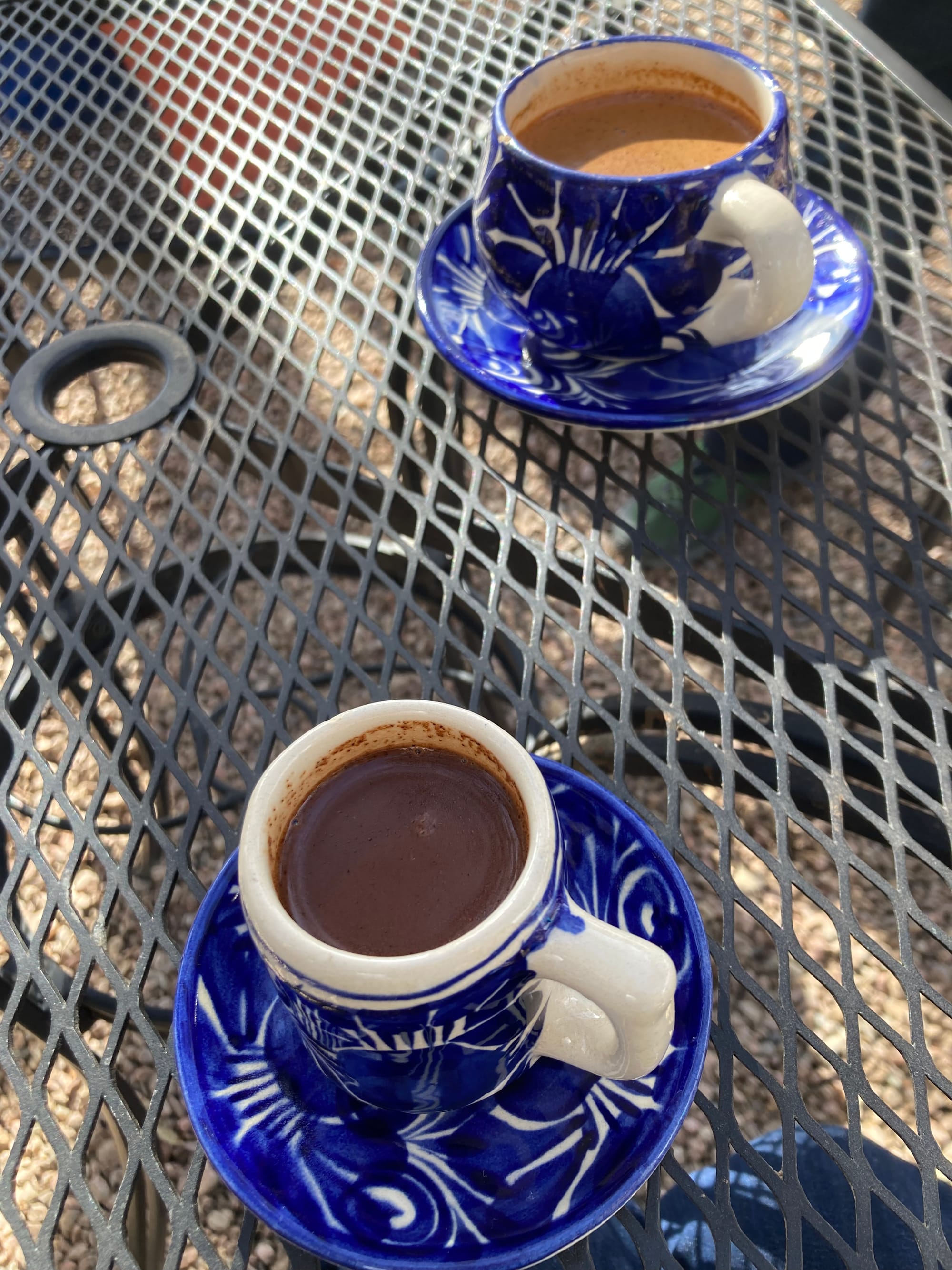 Hot chocolate in blue and white ceramic cups on top of a metal table outdoors