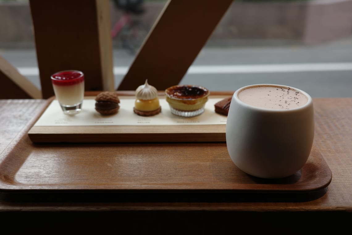 A cup of hot chocolate on a tray with a platter of sweet treats.