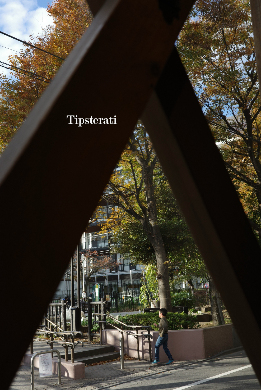 Wooden beams in a window in the shape of an inverted V frame a young boy heading towards a playground.